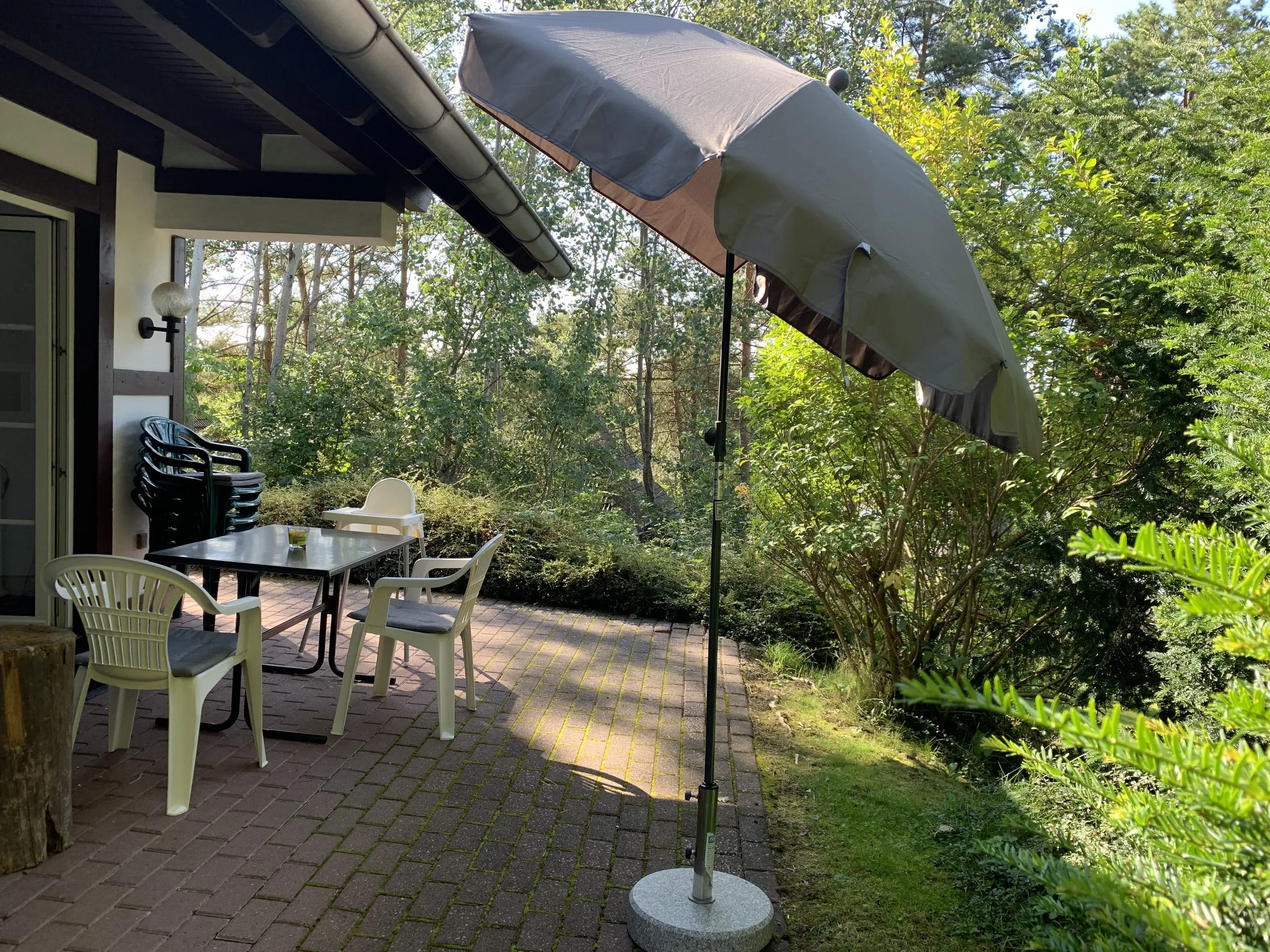 Terrasse mit Gartenmöbeln und Sonnenschirm im Grünen
